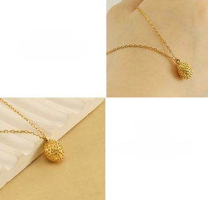 Macro detail of 18k gold plated stainless steel durian texture pendant on cross chain
