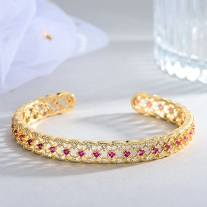 Detail of 18k gold plated open cuff bracelet with mesh hollow design and ruby red crystals