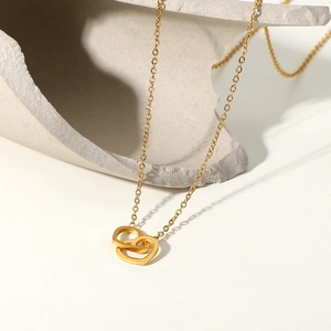 Dettaglio della collana con ciondolo a doppio cuore in oro 18K su trama di pietra