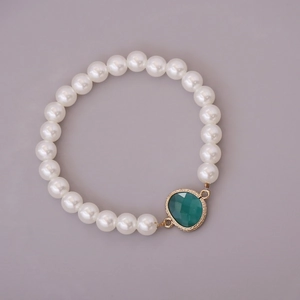 Detail of white glass pearl bracelet featuring a green gemstone pendant with gold trim