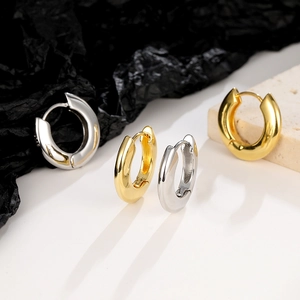 Pair of minimalist round chunky hoop earrings in gold and silver finishes on stone