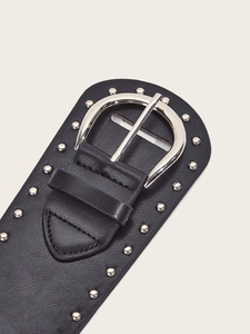 Close-up of black punk belt with silver round studs and large horseshoe buckle detail