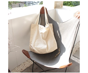 Beige canvas tote bag on a modern leather chair in an outdoor patio setting