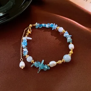 Elegant aquamarine and pearl beaded necklace with gold textured accents and a drop charm