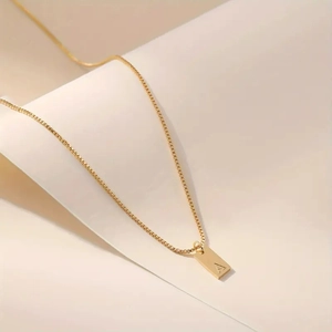 Macro shot of 14K gold plated box chain and rectangular pendant with letter A engraving