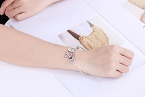 Detailed view of silver stainless steel Mom heart charm bracelet worn on a wrist