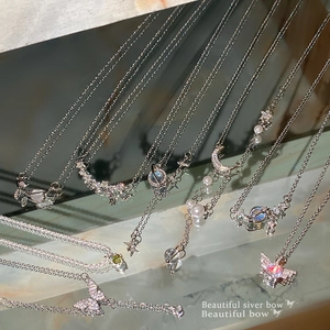 Sparkling butterfly and planet titanium steel necklaces displayed on a marble surface