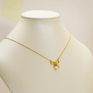 Collier élégant en or 18 carats avec pendentif nœud et perle blanche sur buste