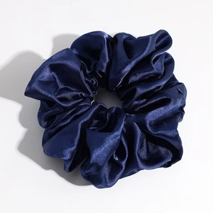 Detailed view of glossy dark blue satin scrunchie showing fabric texture and soft pleats