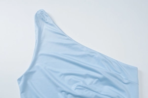 Detailed view of asymmetric light blue one-shoulder top with smooth fabric texture