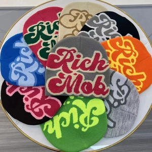 Top view of colorful knit beanies with Rich Mob lettering arranged on a white table