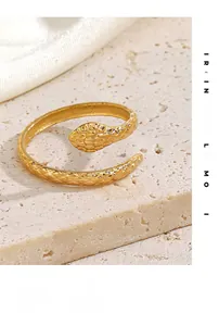 Macro shot of gold-plated snake ring with intricate scale texture on a stone pedestal