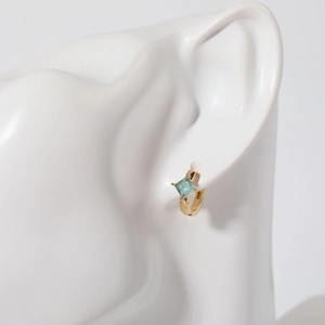 Minimalist gold rhombus earrings with light blue square stone on a model's ear