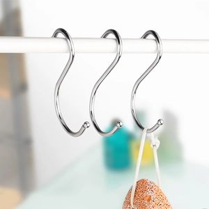 Three silver metal S-shaped hooks on a rod holding a pumice stone in a bathroom setup