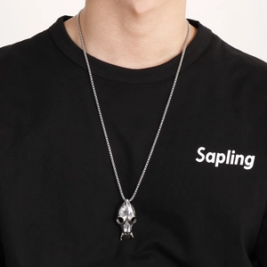 Detailed view of silver animal skull pendant on a box chain worn by a model