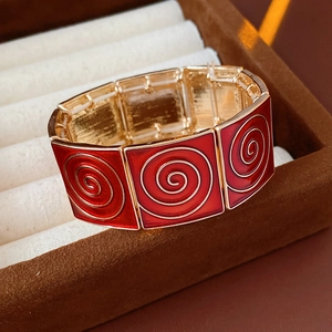 Detail of vintage red enamel bangle with golden spiral texture and elastic square link design