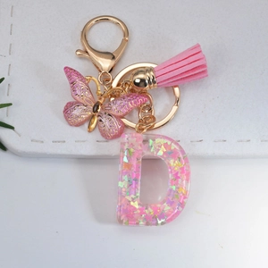 Pink resin letter D keychain with glitter, butterfly charm, and leather tassel on gold ring