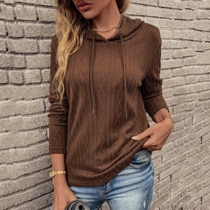 Dettaglio di felpa con cappuccio in maglia a trecce marrone scuro con trama a rombi e laccio