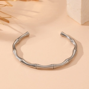 Detail view of silver bamboo joint bangle on a minimalist neutral textured background