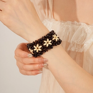 Detail of bohemian coconut shell stretch bracelet with floral woven pattern