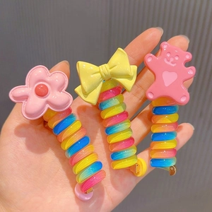 Close-up of rainbow spiral hair ties with pink flower, yellow bow, and pink bear charms
