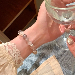Dettaglio del bracciale con perle di pietre naturali rosa, grigie e beige al polso