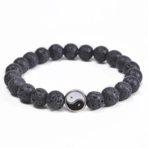 Close-up of black volcanic lava beads and silver Yin Yang charm on an elastic bracelet