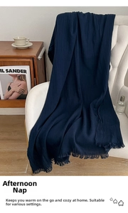 Close-up of deep blue meditation shawl with tassels on a white chair in a cozy interior