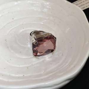 Close-up of a large rectangular pink gemstone ring on a white textured ceramic dish