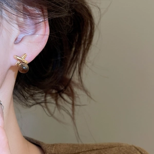 Close-up of vintage 18k gold plated X-cross stud earrings with brown tiger eye beads