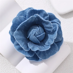 Close-up of layered blue denim camellia flower brooch with frayed edges and texture