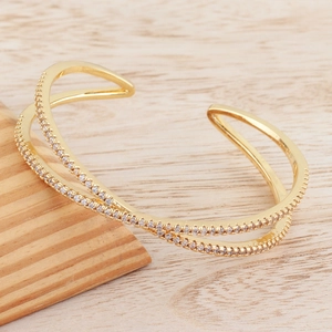 Macro shot of gold-plated crossover open bangle with pavé-set cubic zirconia accents