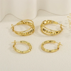 Detail of two pairs of gold plated earrings featuring layered hollow and textured designs