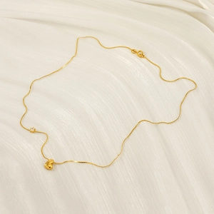 Golden heart necklace with cubic zirconia accent on white silk background