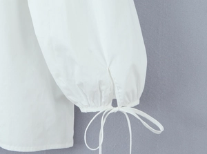 Detail of white blouse lantern sleeve with adjustable tie-up bow cuff design