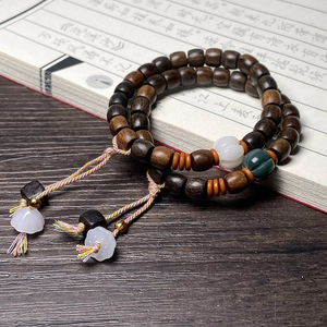 Detail of dark brown wood prayer beads with white pumpkin spacers on calligraphy book