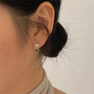 Minimalist 925 sterling silver heart studs with black round pendants on a model ear