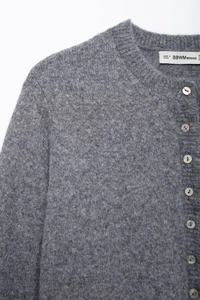 Detail of grey knit cardigan with pearlescent buttons and soft fuzzy texture fabric