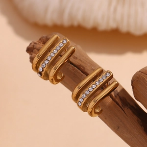 Detailed macro view of 18K gold plated J-shape earrings with rhinestones on a wood branch