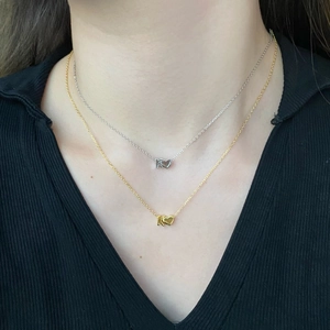 Detail of silver and gold heart necklaces with letter K pendant on a model's neck