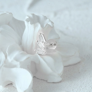 Macro shot of silver crescent stud earring with rectangular gems on ceramic flower