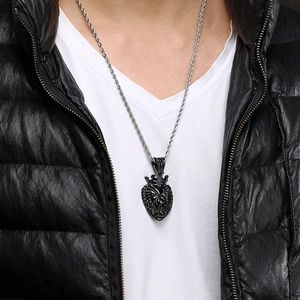 Detail of a black roaring lion head pendant on a silver rope chain worn by a male model