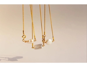 Macro shot of three unique baroque pearls on a gold snake chain necklace