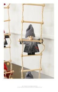 Detail of grey knitted gnome climbing wooden ladder for Christmas tree decor