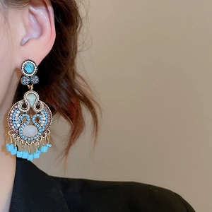 Close-up of model wearing bohemian vintage turquoise earrings with tassel detail