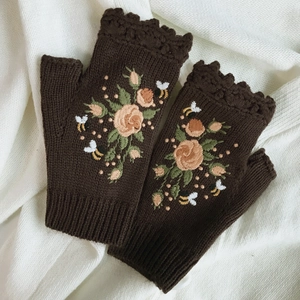 Close-up of winter knit fingerless gloves with detailed bee and floral embroidery