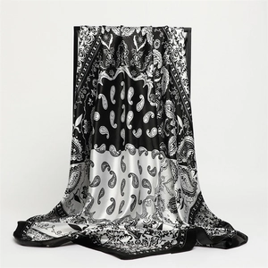Two-tone black and white paisley silk scarf displayed elegantly on a professional stand
