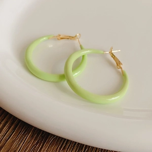 Detail of light green round hoop earrings with gold hooks on a white ceramic plate