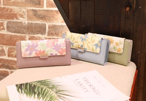 Detailed view of floral print wallets in pink, light blue, and green with metal buckles