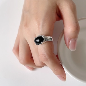 Close-up of vintage silver ring featuring a large oval black onyx stone on a person's finger
